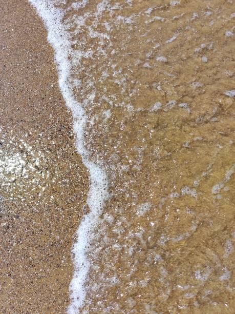 istock Foamy sea wave reaching the beach sands 2158963526