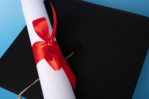 istock Graduation cap and diploma on blue background, learning and knowledge, university graduation ceremony 2158964776