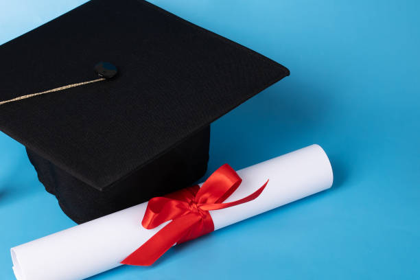 istock Graduation cap and diploma on blue background, college student graduating, education and learning milestone 2158964788