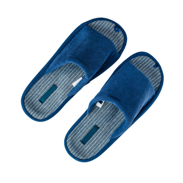 Closeup of a new pair of generic, mass produced slippers on a wood grain floor.