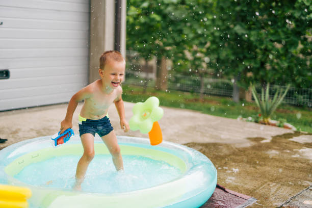 istock one boy have fun in pool, water gun toy 2158968058