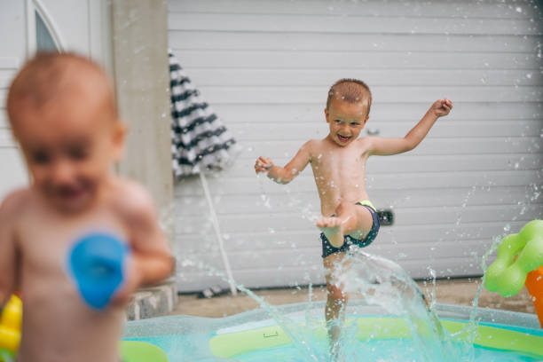istock two boys are having fun in the pool, water gun toy 2158969409