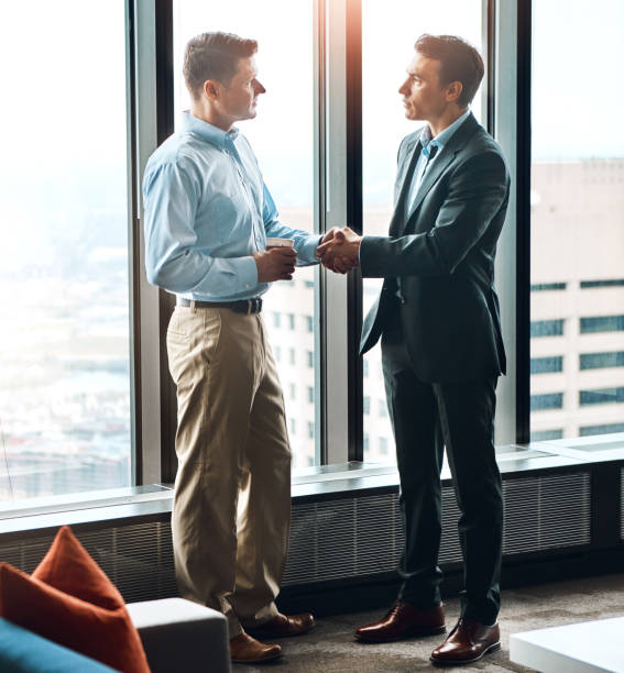 istock Window, handshake and men in office for hiring, welcome and onboarding in modern workplace. Partnership, support and business people in Seattle for collaboration, deal and agreement for project 2158971619