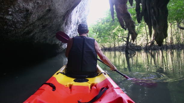 istock Kayaker rows with paddle navigating close to cliff in canyon 2158971917