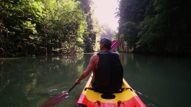 istock Tourist rows with paddle navigating kayak in calm river 2158972477