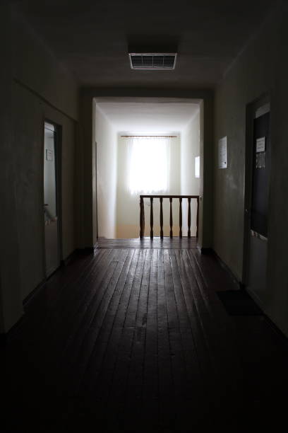 A dark hallway with a door. Wall. Indoor. Building. Bed. Floor