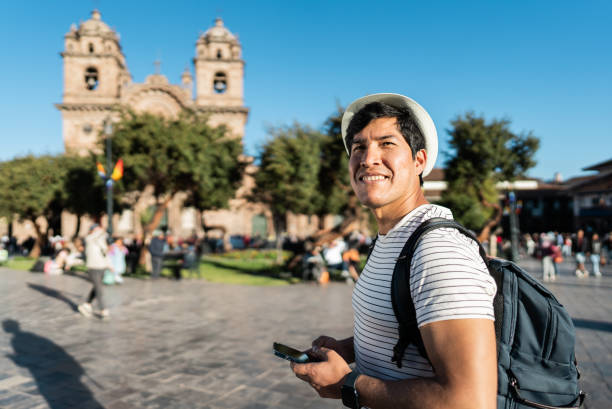 Mid adult traveler man walking and using mobile phone on Cusco, Peru