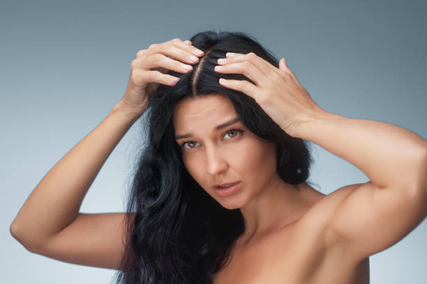 Concerned Asian Woman Examining Hair for Hair Loss and Gray Hair Concerned Asian woman examines her scalp, highlighting issues like hair loss and gray hair. Ideal for advertisements promoting treatment products, shampoos, and hair care solutions. gray hair young woman stock pictures, royalty-free photos & images