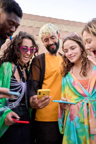 istock Side view multiracial smiling group young generation z leaning brick wall using phones outdoor. 2158980199