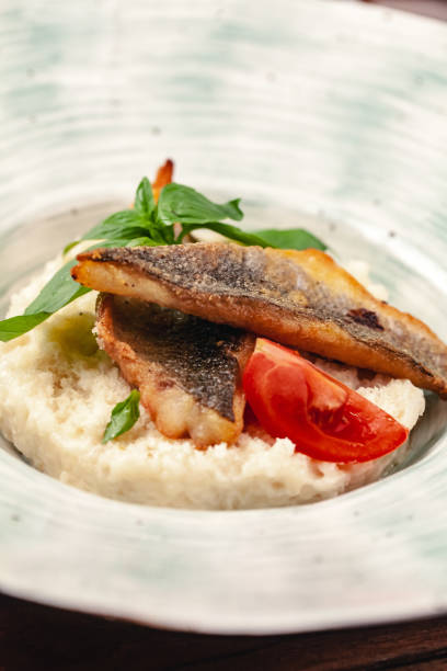 istock fish grill dish baked whole grilled on a plate with vegetables and lemon 2158981666