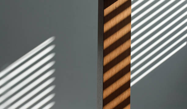 istock Shadow from venetian blind falling across a wall and table leg. Surreal optical illusion 2158988792