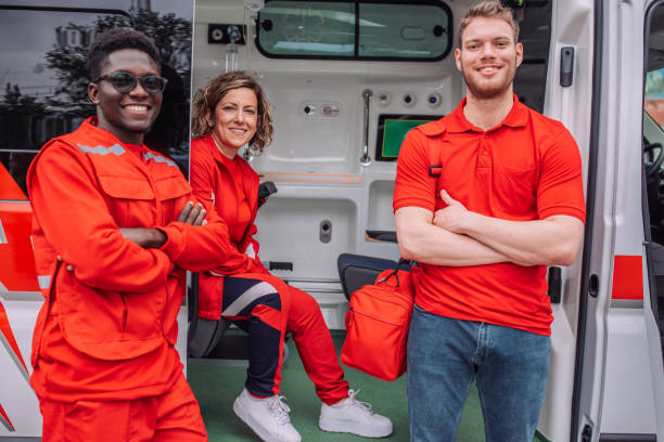 Paramedic team smiling posing with arms crossed by ambulance