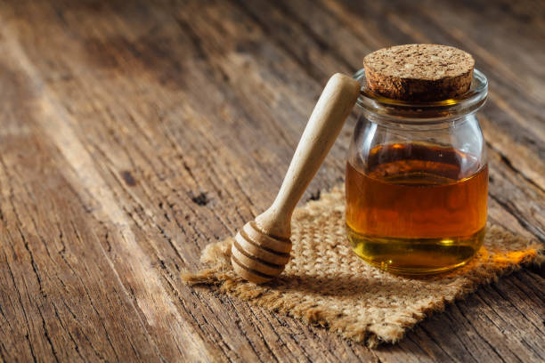 istock honey in glass bottle on wooden background 2158994752