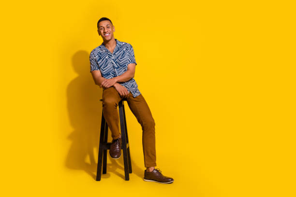 istock Full length photo of funky cool guy dressed print shirt sitting stool empty space isolated yellow color background 2158994864