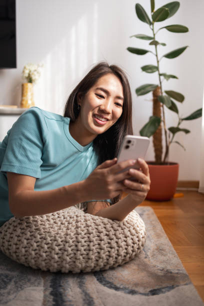 Asian woman happily using her smartphone at home