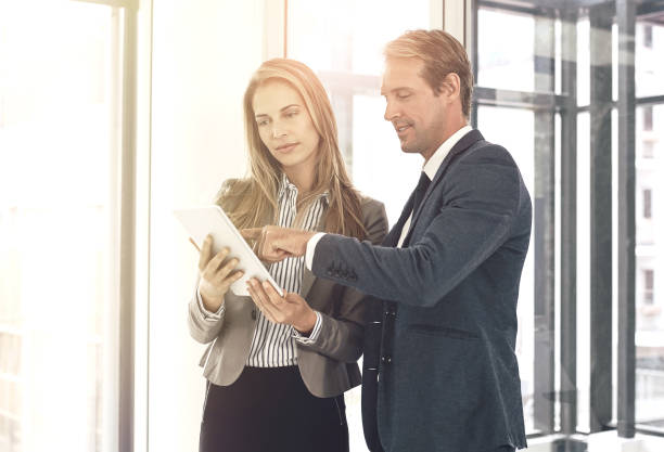 istock Business people, partnership and tablet with discussion in office for briefing on b2b collaboration or project management. Teamwork, digital tech or meeting on company growth and review on kpi goals 2158997299