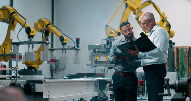 istock Robotics, people and engineer or teamwork plans with industrial project and working in warehouse. Factory, engineering and futuristic work of manufacturing management with talk for cnc automation 2158997921