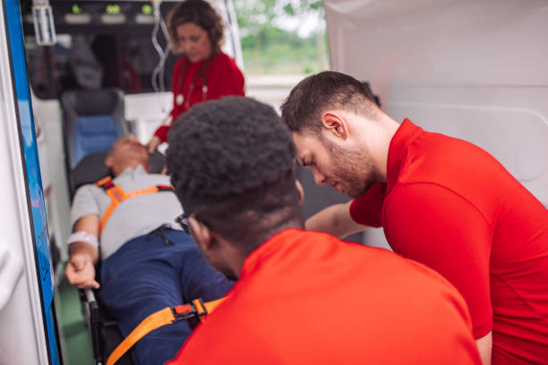 Emergency medical technicians providing care to a patient on a stretcher inside an ambulance