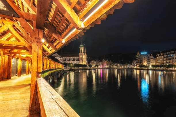 Evening panorama of the skyline with the Stadsbrug and Nieuwe Toren of the city of Kampen in Overijssel, The Netherlands. The lights of the city are reflected in the calm water while clouds are moving over the city in the sky.