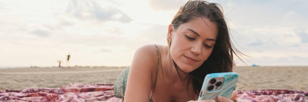 istock Young smiling woman relaxing on the beach and using mobile phone 2159004602