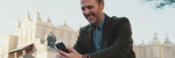 istock Middle aged man talking on mobile phone on old town background, panorama 2159004848