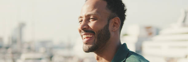 istock Young laughing happy man sitting in harbor with yachts on background 2159006295