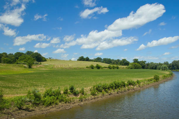 Sunny Summer landscape view of the Missouri River flowing by lush, hilly green farmland along the Katy Trail, near Jefferson City, Missouri.