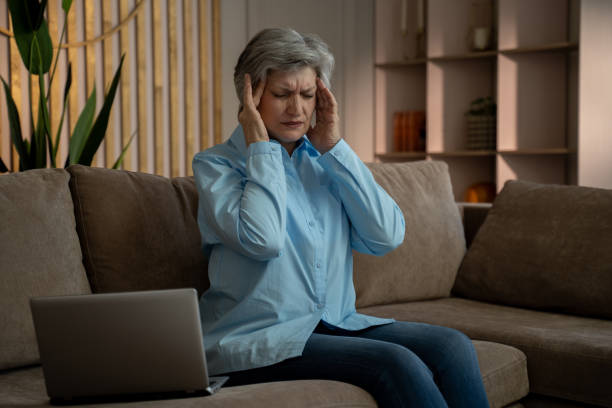 istock Elderly woman experiencing a headache while working on her laptop at home. 2159007908