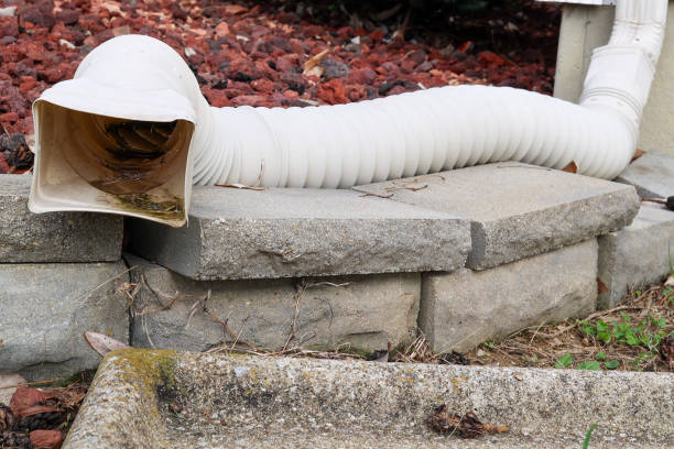 Close-up view of the bottom part of a gutter system downspout vertical drainage elbow pipe
