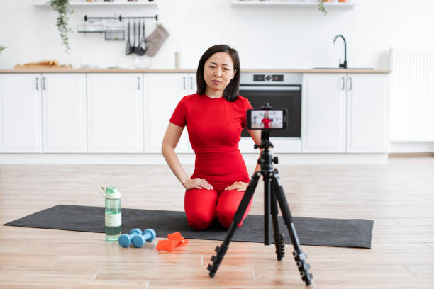 istock Woman recording online yoga class in modern kitchen 2159010189