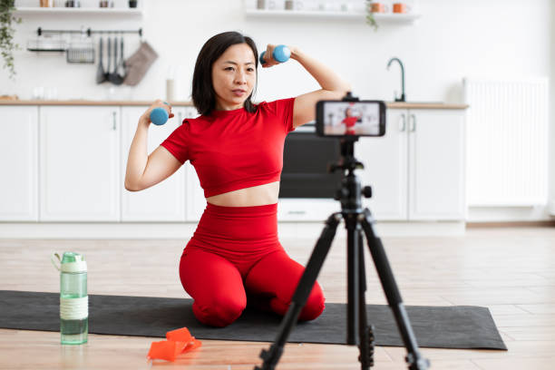 istock Woman exercising at home with dumbbells recording workout video 2159010206
