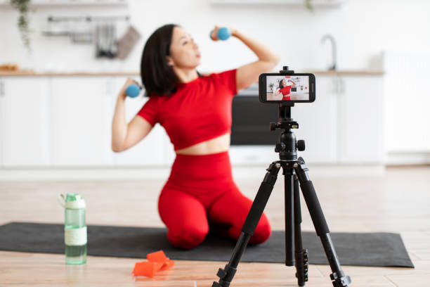istock Woman filming home workout with dumbbells and tripod 2159010213