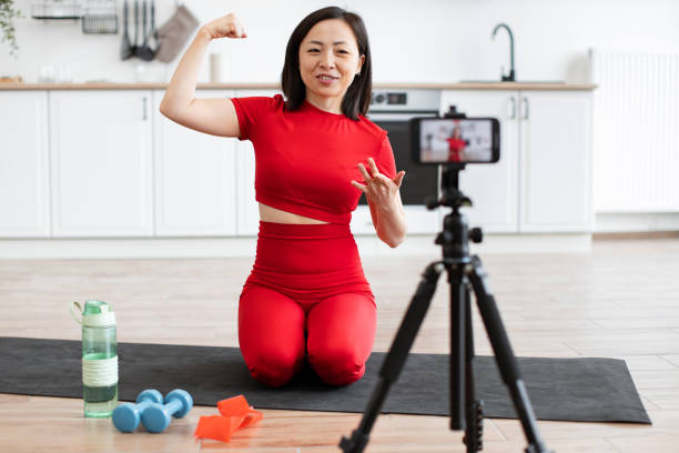 istock Woman filming fitness tutorial at home flexing arm muscle 2159010217