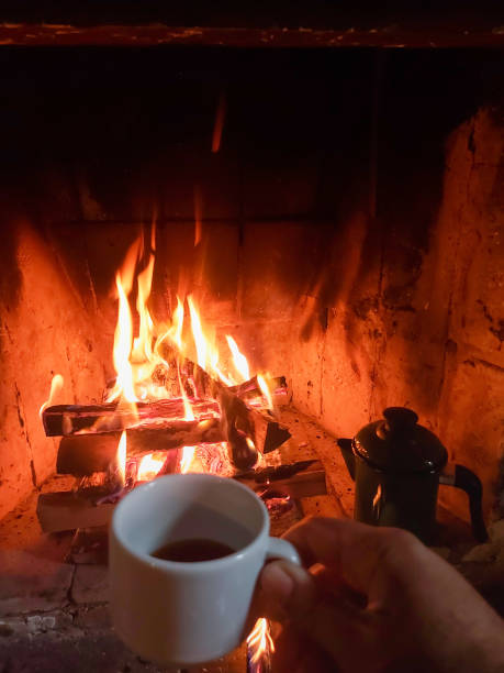 Person drinking coffee in front of fireplace