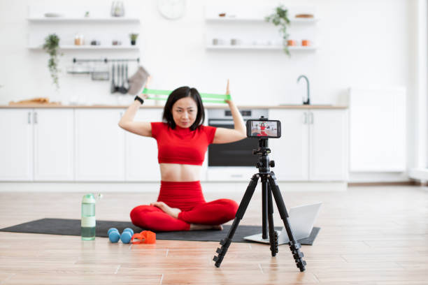 istock Woman filming fitness tutorial at home with resistance bands 2159011679