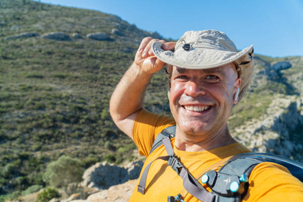 Alone hipster man wearing hat with digital camera on his hands looking at view in the mountains