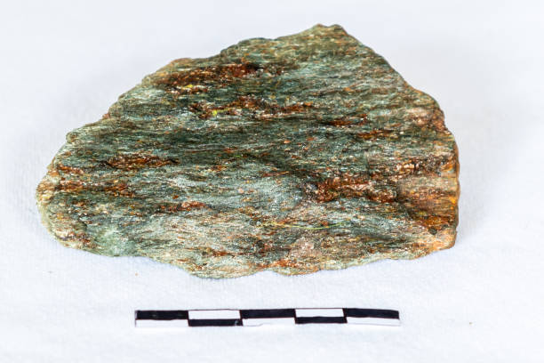A sample of bright apple-green chlorite schist with a 5cm scale on a white background