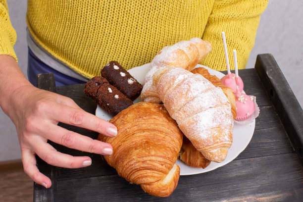 Hands hold a tray with sweets and pastries.