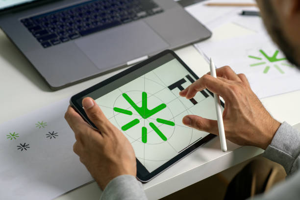 istock Close-up shot of a graphic designer making notes on logo designs, using a tablet, designing logos, and showcasing the corporate identity and logo design process. 2159021517