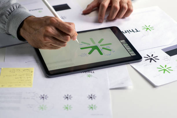 istock Close-up shot of a graphic designer making notes on logo designs, using a tablet, designing logos, and showcasing the corporate identity and logo design process. 2159021564