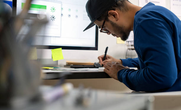 istock Candid shot of Asian graphic designer inspecting logo designs, using computers, designing logos, and showcasing the corporate identity and logo design process. 2159021780