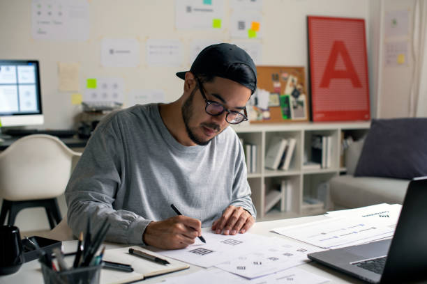 istock Candid shot of Asian graphic designer inspecting logo designs, using computers, designing logos, and showcasing the corporate identity and logo design process. 2159021798