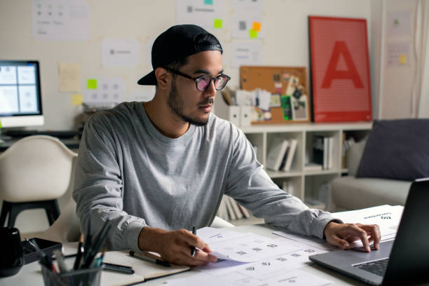istock Candid shot of Asian graphic designer inspecting logo designs, using computers, designing logos, and showcasing the corporate identity and logo design process. 2159021811