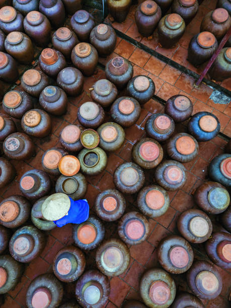 aerial view on one blue collar worker stirring soy sauce in huge clay pod standing in a row