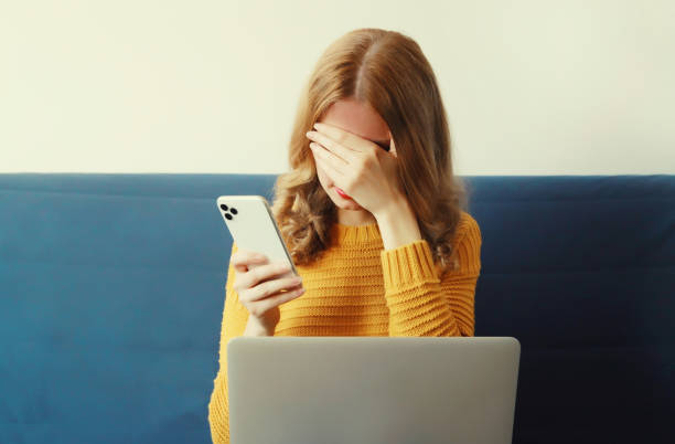 istock Sad upset crying woman holding phone suffering from headache, migraine while working with laptop 2159023995