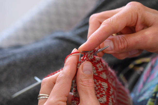 istock woman sitting on sofa, skillfully knitting warm socks 1 2159024479