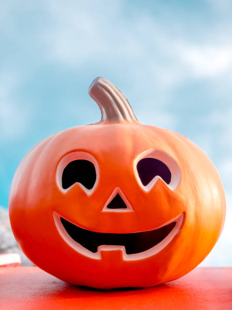 istock Red Halloween Jack o Lantern Pumpkin with funny smiling face on blue sky background. Orange pumpkin head smile face with open mouth, vertical style. Happy Halloween day minimal background concept. 2159028238
