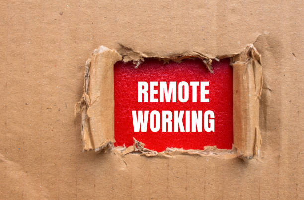 istock Remote working message written on ripped cardboard paper with red background 2159028413