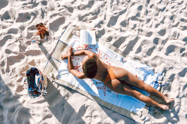 istock Young woman sunbathing at the beach 2159033410