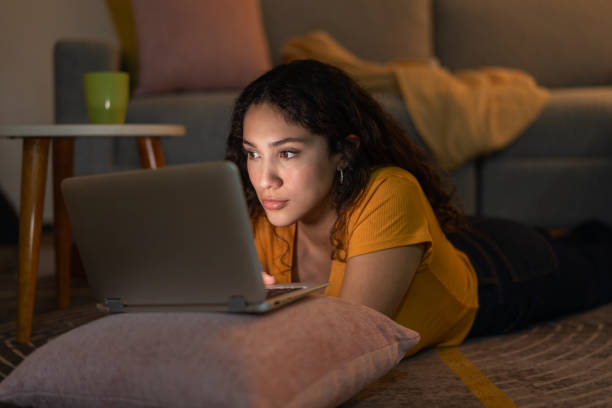 istock Young woman using laptop, lying on living room floor 2159039387